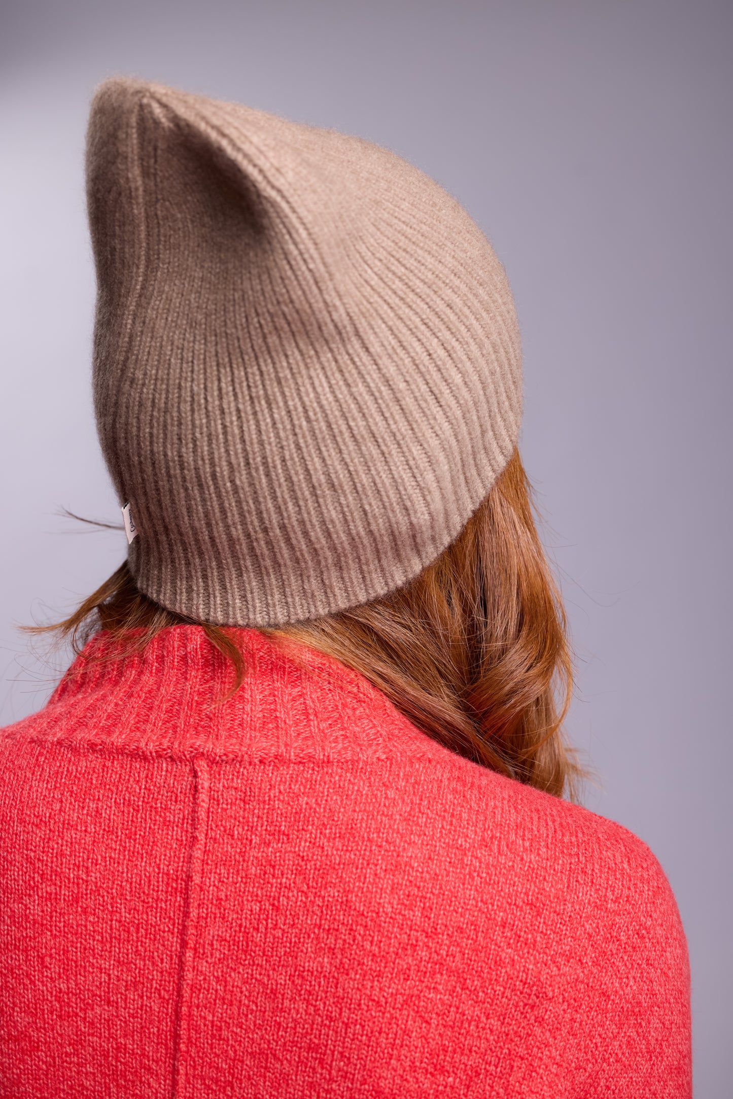 The cashmere hat features a snug fit with a vertically ribbed texture, providing a stylish yet minimalist design. The clean silhouette and classic ribbing make it a versatile accessory suitable for various casual or semi-formal outfits.