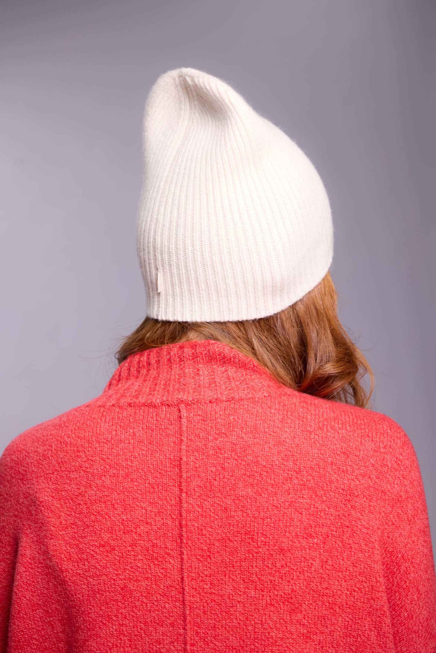 The cashmere hat features a snug fit with a vertically ribbed texture, providing a stylish yet minimalist design. The clean silhouette and classic ribbing make it a versatile accessory suitable for various casual or semi-formal outfits.