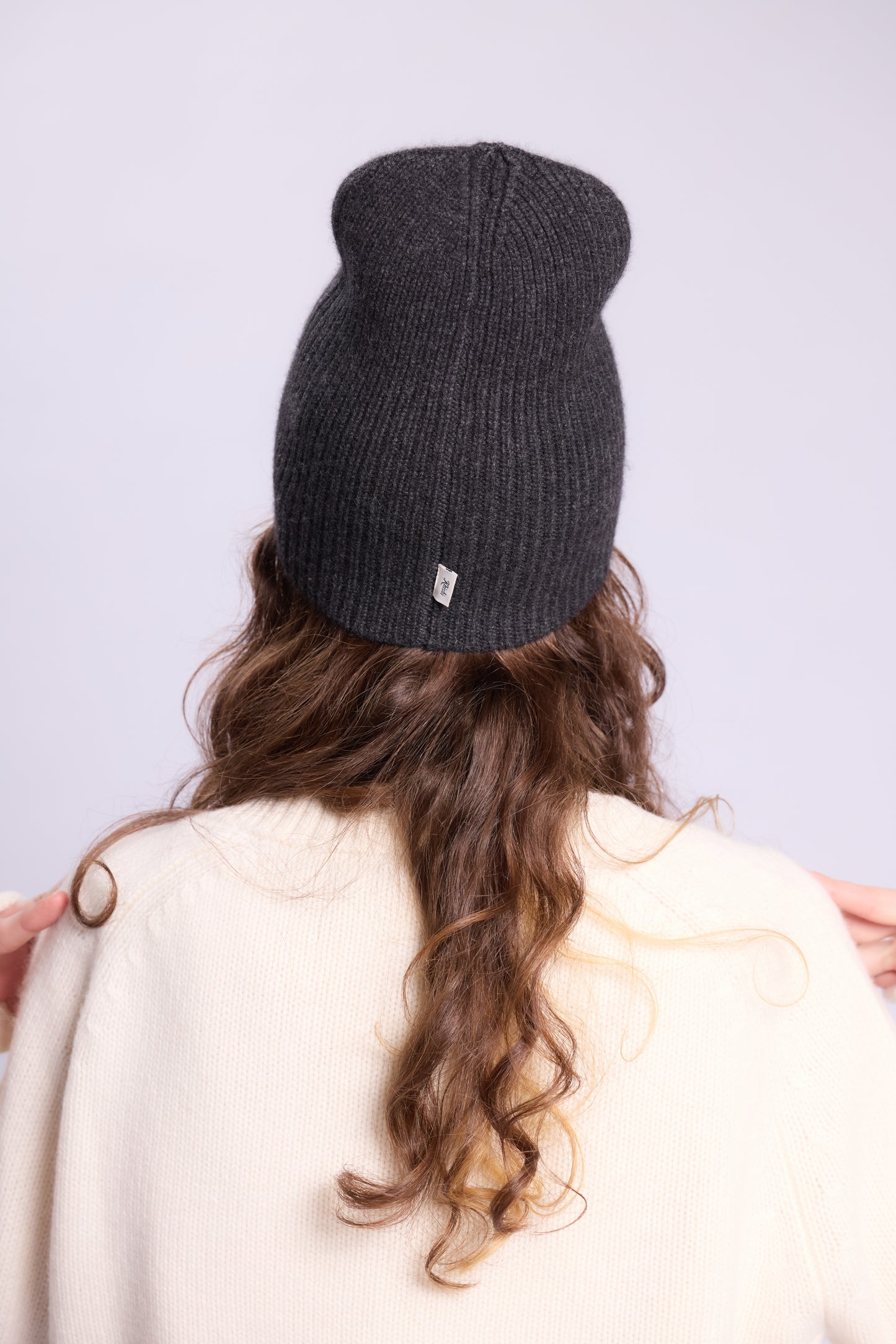 The cashmere hat features a snug fit with a vertically ribbed texture, providing a stylish yet minimalist design. The clean silhouette and classic ribbing make it a versatile accessory suitable for various casual or semi-formal outfits.