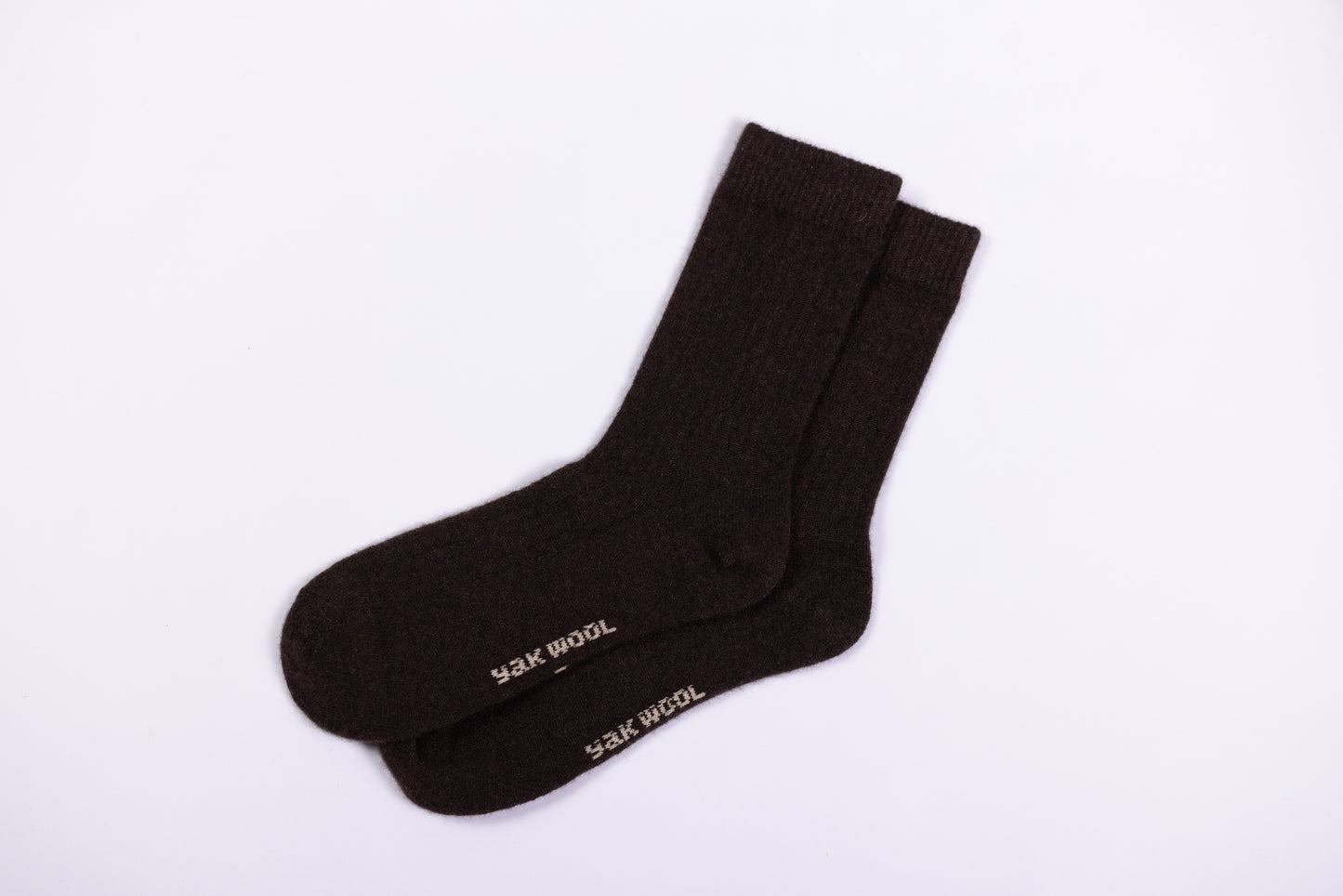 This image showcases a pair of dark brown yak wool socks. These socks feature a classic crew length, with a ribbed texture at the top for a snug and secure fit. The fabric appears thick and cozy, characteristic of yak wool, which is known for its exceptional warmth, softness, and durability.