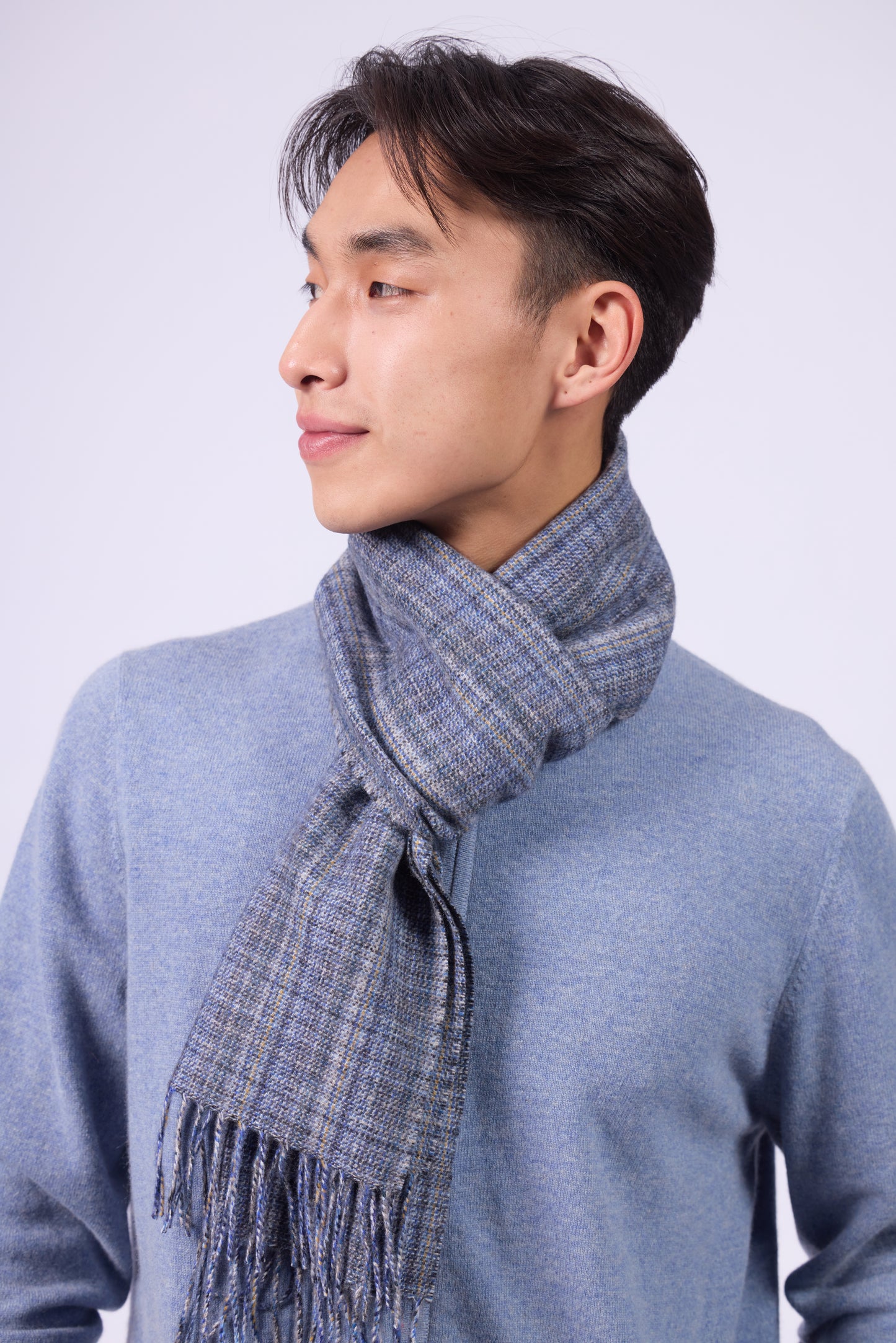 This scarf is a unisex 100% cashmere woven scarf, featuring a classic plaid pattern with a mix of pink, purple, and gray tones.