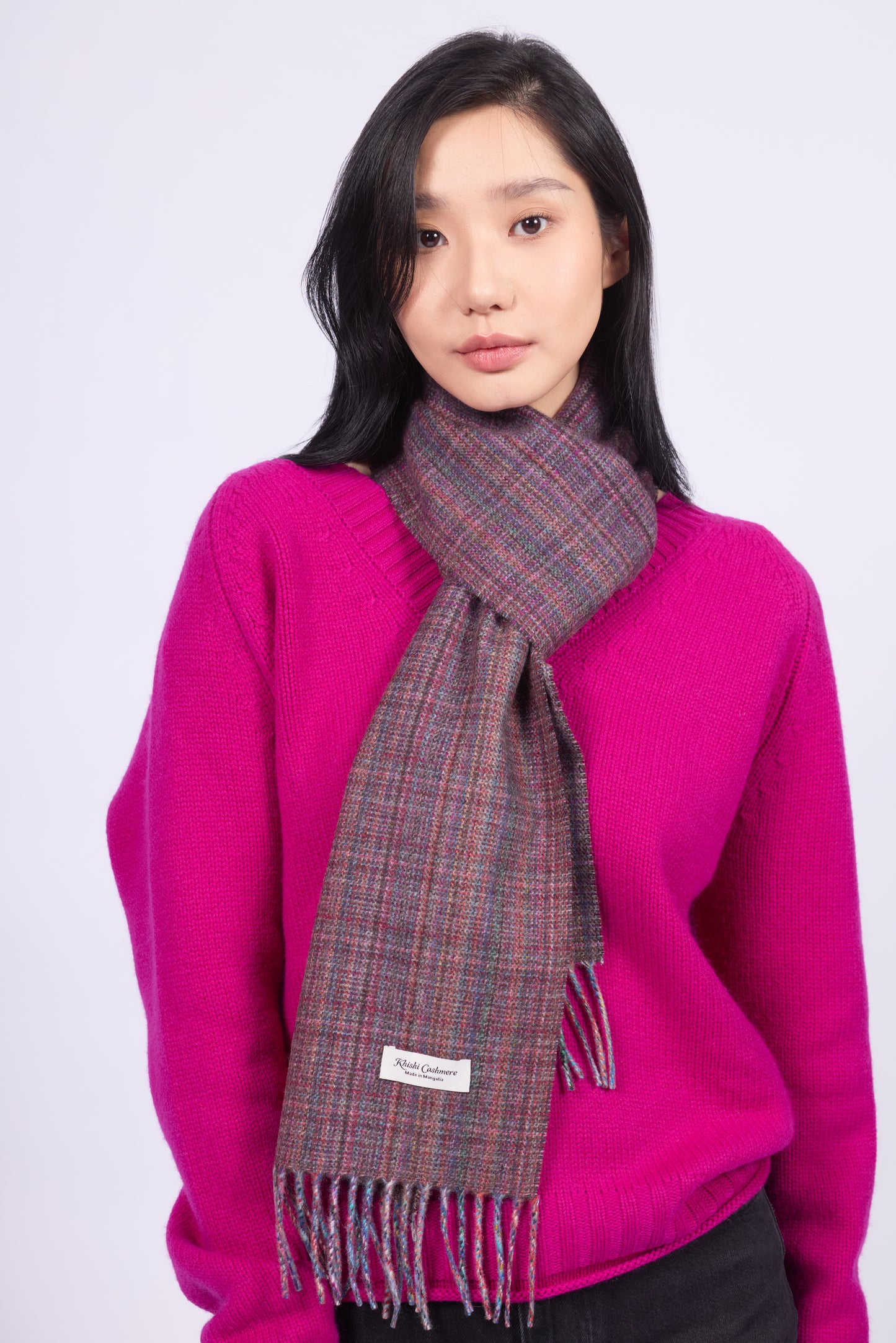 This scarf is a unisex 100% cashmere woven scarf, featuring a classic plaid pattern with a mix of pink, purple, and gray tones.
