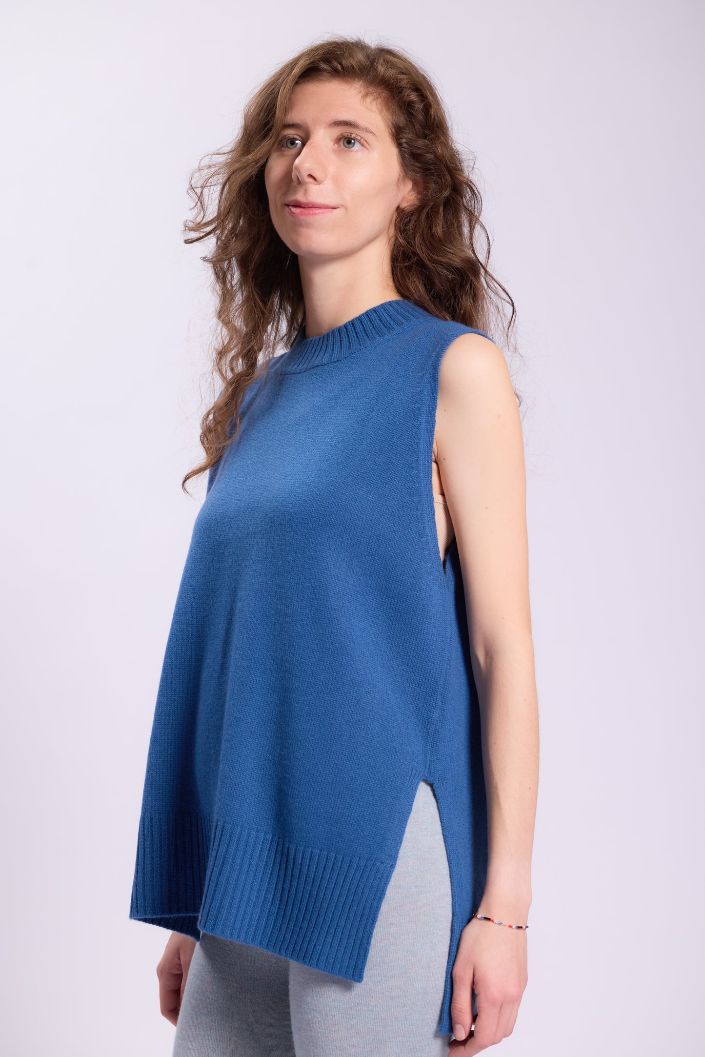 Cashmere long vest with ribbed crew neck style and wide hem for a clean and minimalist look. The side slits add a touch of casual style, making it versatile and suitable for layering over shirts or wearing on its own.