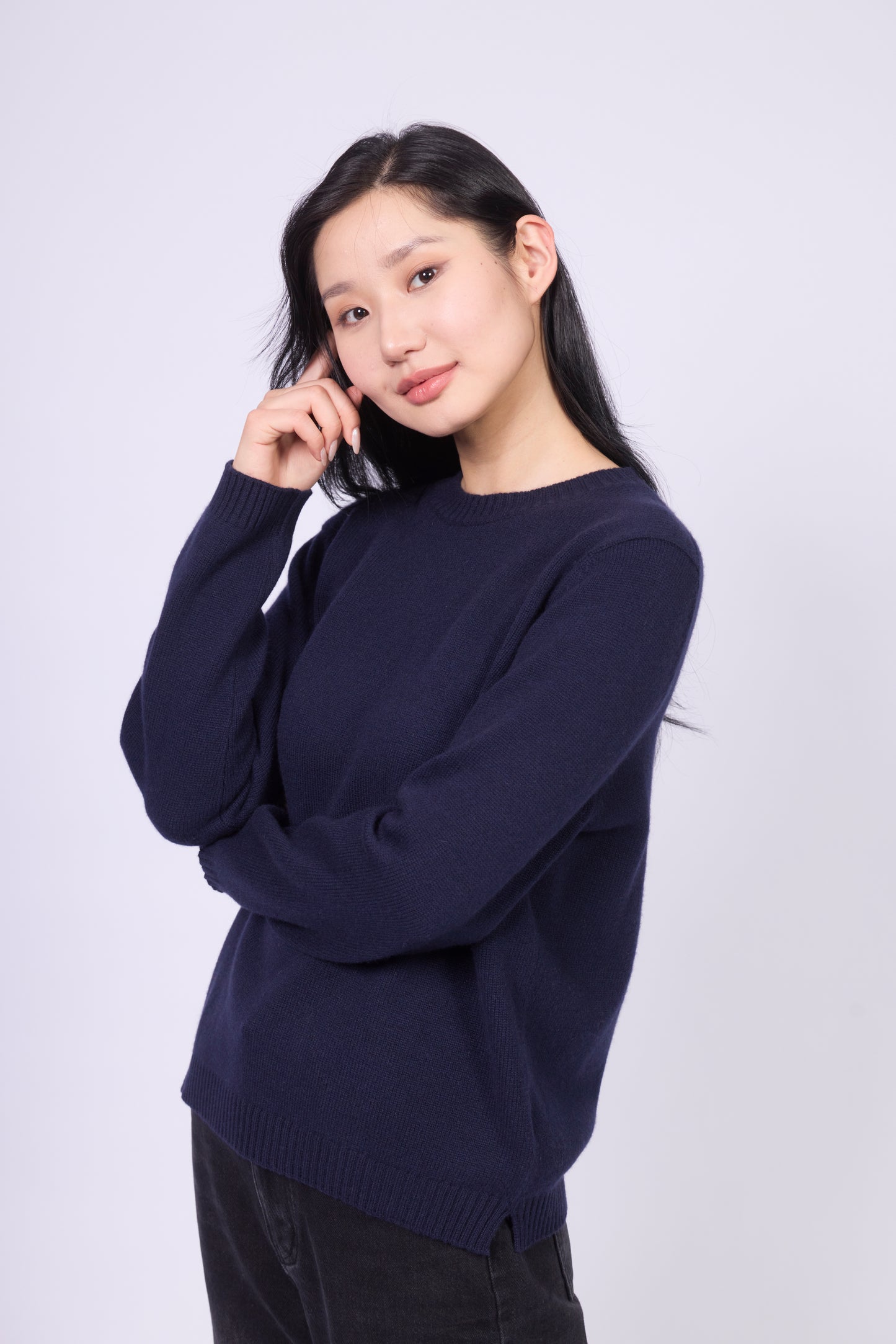 This is a cashmere sweater featuring a crew neckline with ribbed detailing in navy color. The fabric appears soft and cozy, ideal for cooler weather. The cuffs and hem are ribbed, providing a snug and structured fit. It is styled here with light-washed denim, showcasing a casual yet polished look.