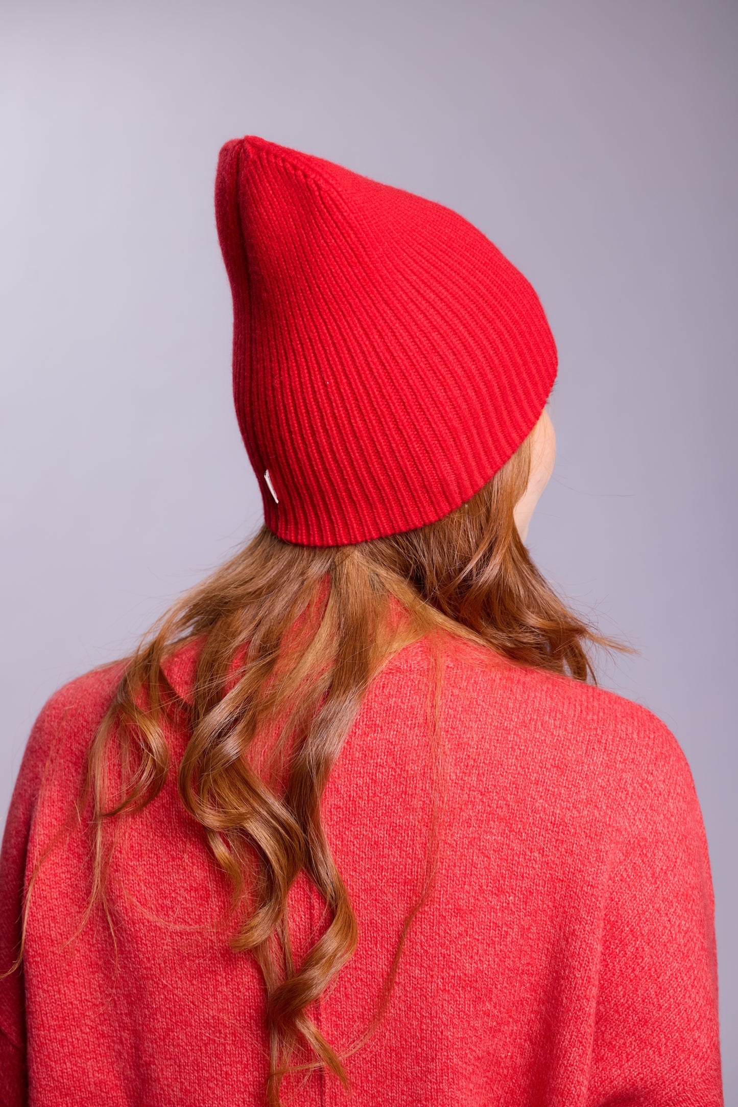 The cashmere hat features a snug fit with a vertically ribbed texture, providing a stylish yet minimalist design. The clean silhouette and classic ribbing make it a versatile accessory suitable for various casual or semi-formal outfits.