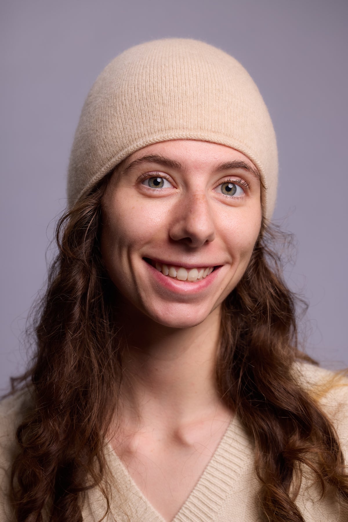 This image features a lightweight, thin cashmere hat in a soft beige color. The hat has a minimalist design, with a snug fit that contours smoothly to the head, offering a sleek and understated look. 